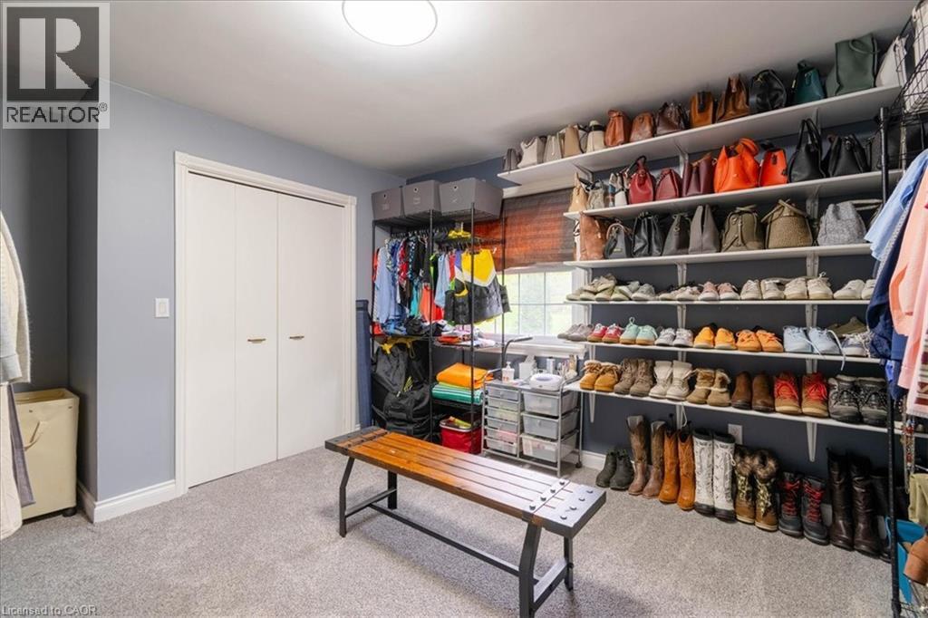 Expansive walk-in closet featuring extensive built-in shelving, carpet flooring, bi-fold closet doors, a rectangular window, and recessed lighting - 111 Decou Road, Simcoe, ON - Indoor