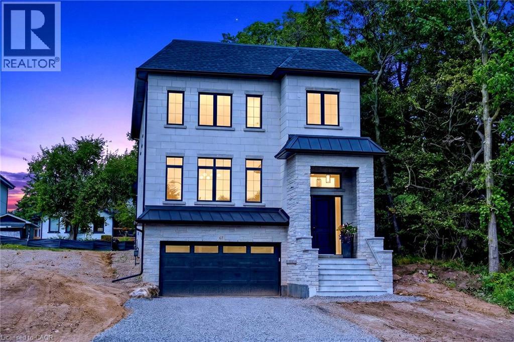 Stone facade with a prominent entry portico, dark-colored roofing, black window frames, and an integrated garage - 67 Cielo Court, Hamilton, ON - Outdoor With Facade
