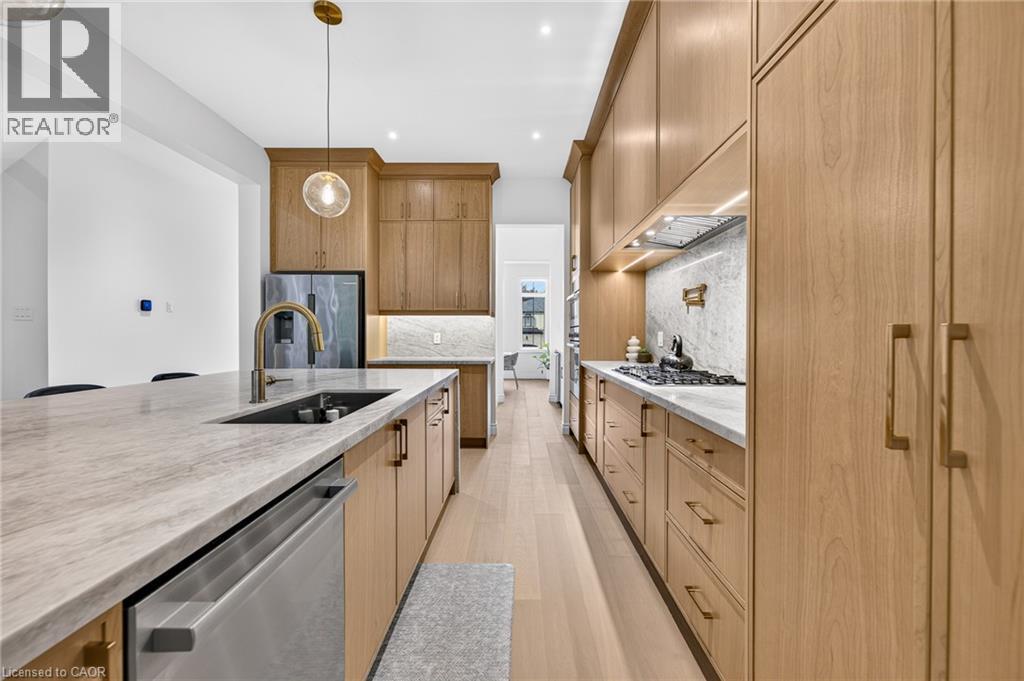 Modern kitchen featuring wood-finish cabinetry, light-toned countertops, and light wood-finish flooring - 67 Cielo Court, Hamilton, ON - Indoor Photo Showing Kitchen With Upgraded Kitchen