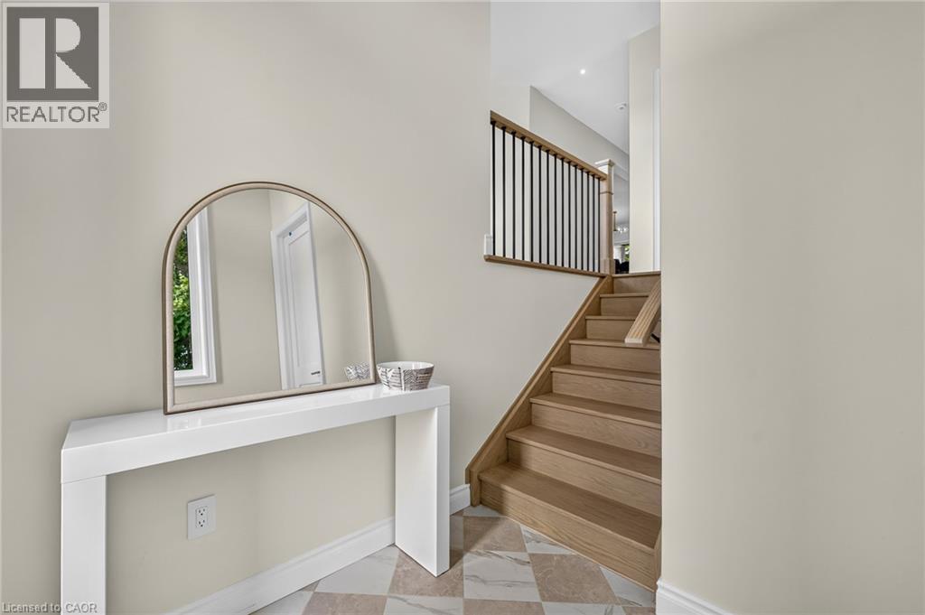 Hardwood staircase with black metal balusters, checkered tile flooring, and a window providing natural illumination - 67 Cielo Court, Hamilton, ON - Indoor Photo Showing Other Room