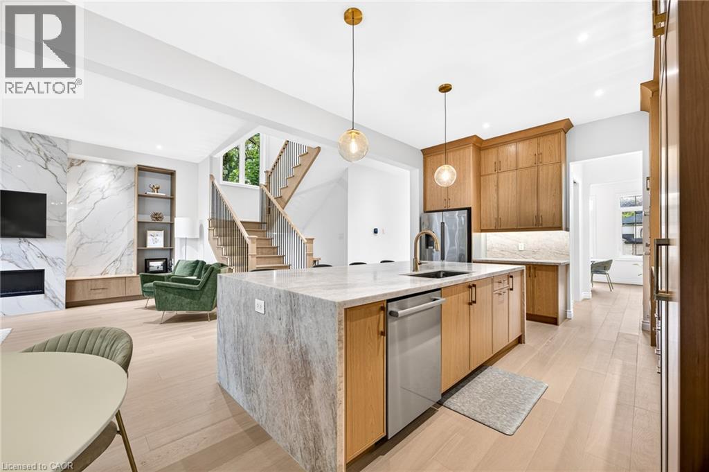 Kitchen island with integrated sink, stainless steel dishwasher, and quartz countertop - 67 Cielo Court, Hamilton, ON - Indoor Photo Showing Kitchen With Fireplace