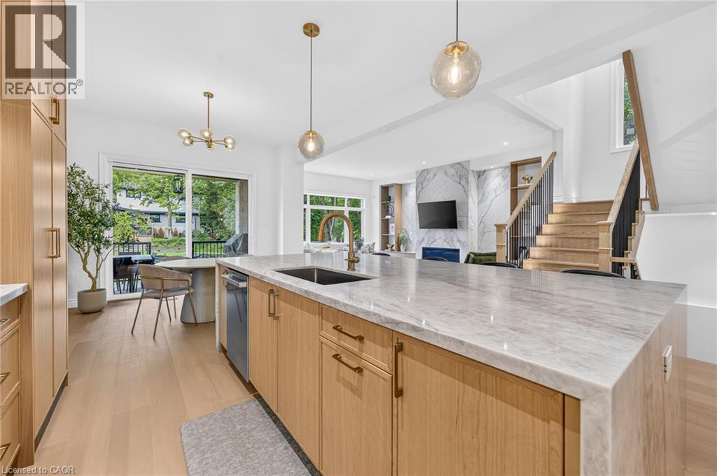 Spacious kitchen island with a stone countertop, light wood-finish cabinetry, and contemporary pendant lighting - 67 Cielo Court, Hamilton, ON - Indoor Photo Showing Kitchen With Upgraded Kitchen