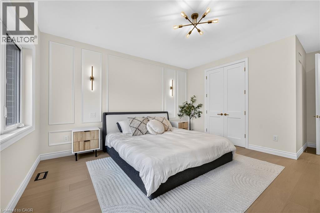 Neutral wall tones with decorative wall molding, wood-finish flooring, and a modern ceiling light fixture - 67 Cielo Court, Hamilton, ON - Indoor Photo Showing Bedroom