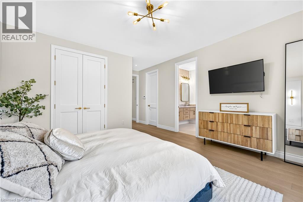Recessed lighting and a modern gold-finish chandelier illuminate this space featuring light wood-finish flooring - 67 Cielo Court, Hamilton, ON - Indoor Photo Showing Bedroom
