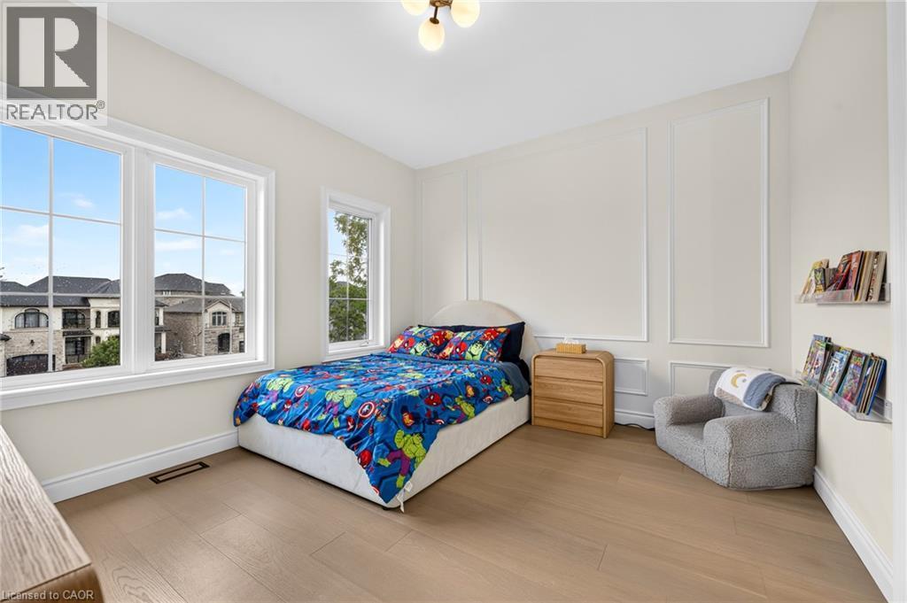 Expansive window arrangement, light wood-finish flooring, accent wall paneling, and a contemporary ceiling light fixture - 67 Cielo Court, Hamilton, ON - Indoor Photo Showing Bedroom