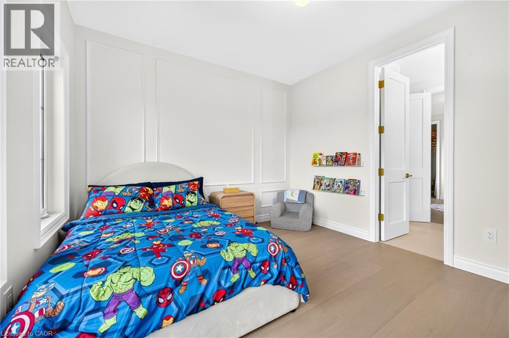 Light wood-finish flooring, white walls with decorative paneling, and a white interior door - 67 Cielo Court, Hamilton, ON - Indoor Photo Showing Bedroom