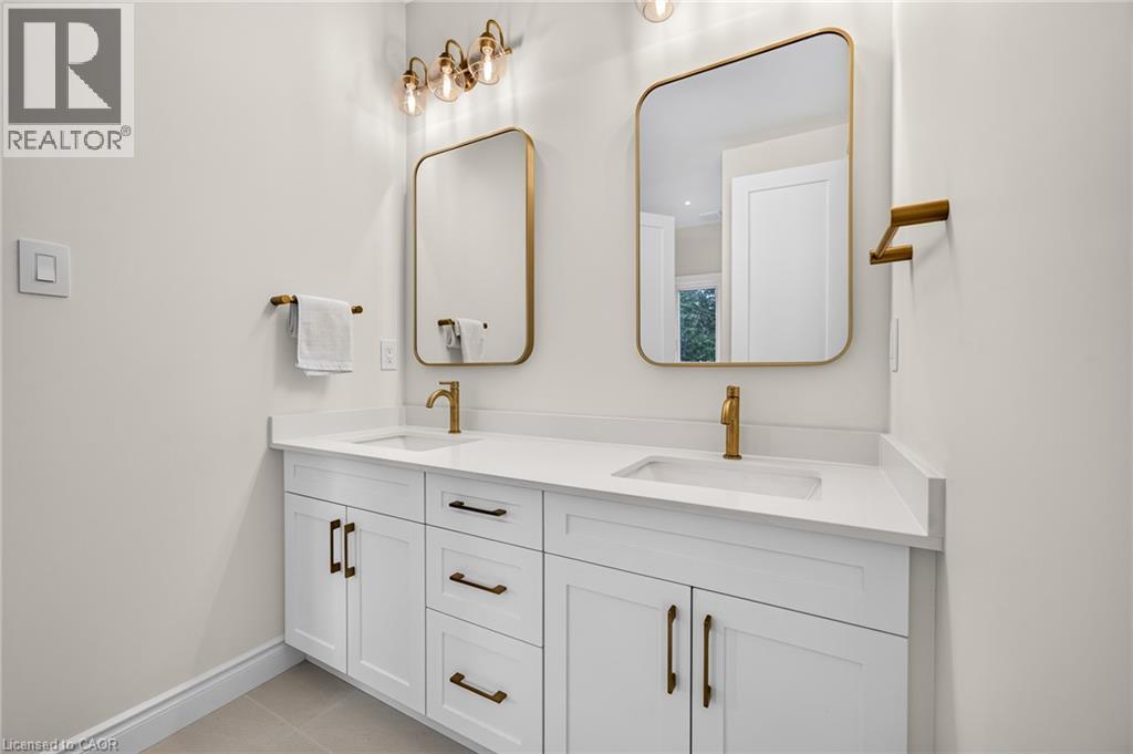 Dual vanity with white cabinetry, gold-finish hardware, rectangular sinks, and integrated countertops - 67 Cielo Court, Hamilton, ON - Indoor Photo Showing Bathroom