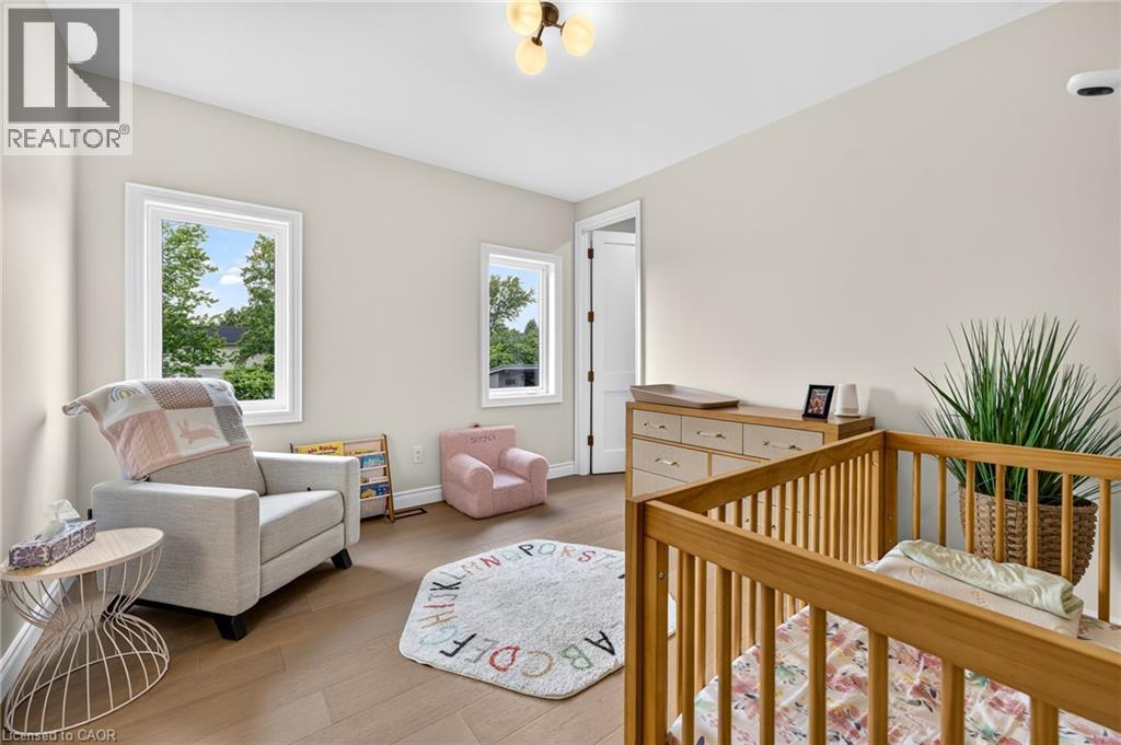 Neutral wall paint, wood-finish flooring, white trim windows, and a ceiling-mounted light fixture - 67 Cielo Court, Hamilton, ON - Indoor Photo Showing Other Room