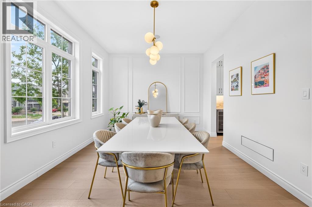 Wide plank wood-finish flooring, white paneled walls, and a multi-globe chandelier - 67 Cielo Court, Hamilton, ON - Indoor Photo Showing Dining Room