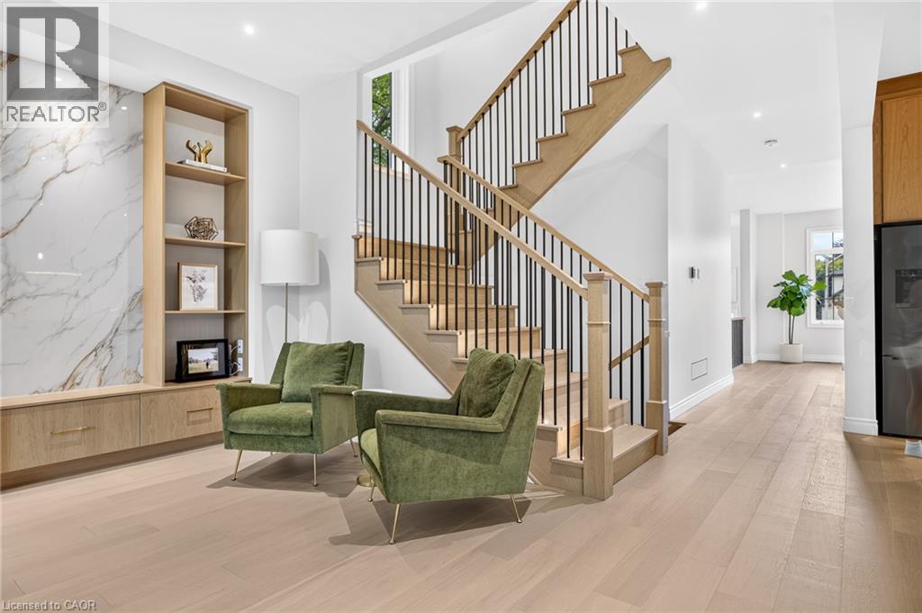 Hardwood flooring, custom built-in cabinetry, large format wall paneling, open-tread staircase with black iron spindles, recessed lighting - 67 Cielo Court, Hamilton, ON - Indoor Photo Showing Other Room