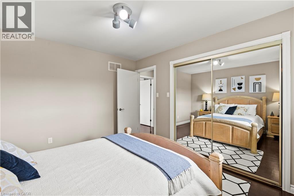 Mirrored closet doors, track lighting fixture, wood-finish flooring, and light wall tones - 87 Monte Drive, Hamilton, ON - Indoor Photo Showing Bedroom
