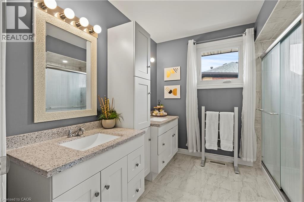 Bathroom featuring a single vanity with a rectangular sink, speckled countertop, white cabinetry, and a glass-enclosed shower - 87 Monte Drive, Hamilton, ON - Indoor Photo Showing Bathroom
