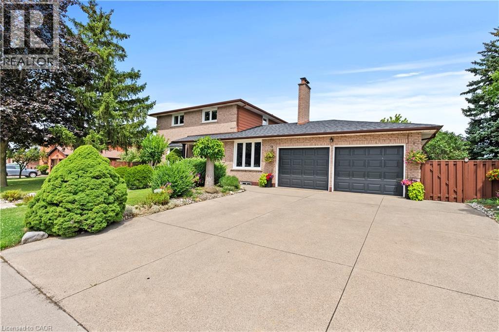 Brick exterior with a prominent chimney, two-car garage, concrete driveway, and established landscaping - 87 Monte Drive, Hamilton, ON - Outdoor