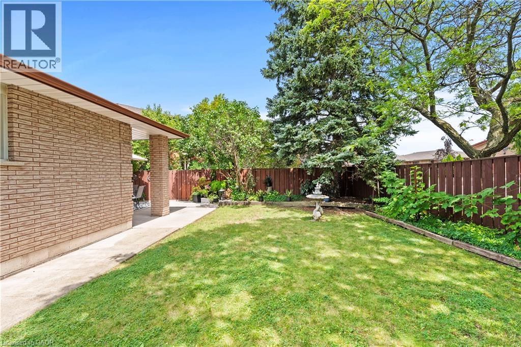 Expansive backyard featuring a manicured lawn, established perimeter landscaping, and a privacy fence - 87 Monte Drive, Hamilton, ON - Outdoor