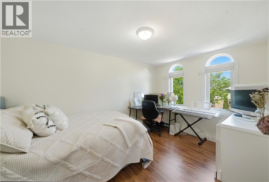 Bedroom featuring wood-finish flooring, light neutral wall paint, and two arched windows - 784 Butternut Avenue, Waterloo, ON - Indoor Photo Showing Bedroom