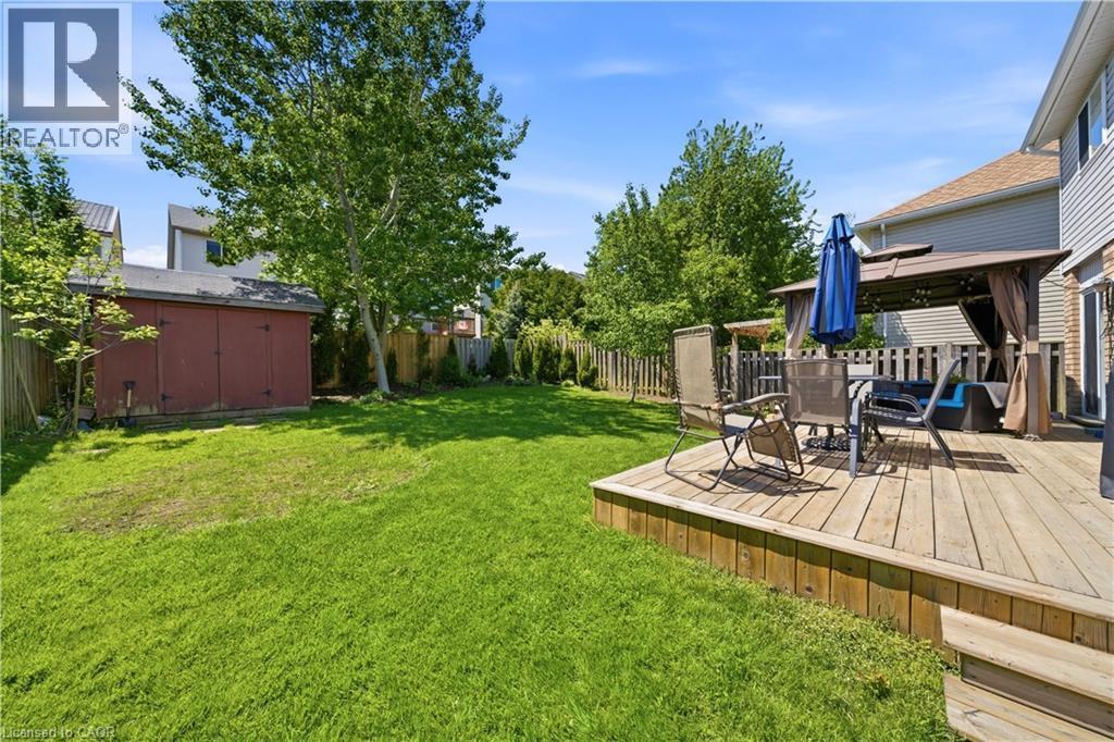 Expansive backyard featuring a wood deck with steps, a wooden privacy fence, mature trees, and a storage shed - 784 Butternut Avenue, Waterloo, ON - Outdoor