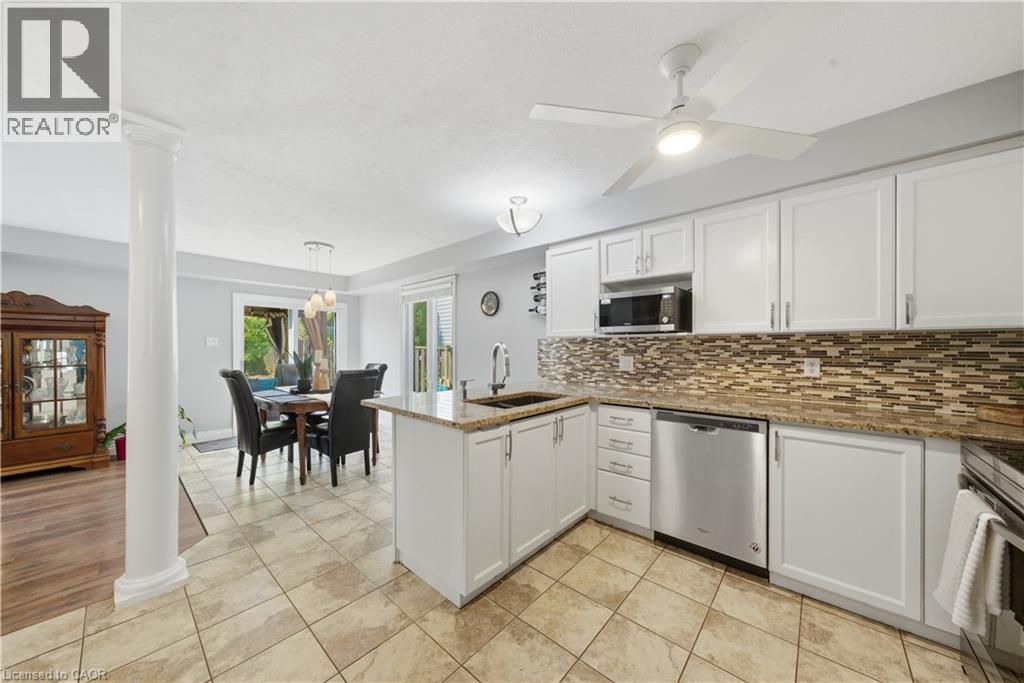 Bright kitchen featuring white shaker cabinetry, granite countertops, stainless steel appliances, and a mosaic tile backsplash - 784 Butternut Avenue, Waterloo, ON - Indoor Photo Showing Kitchen With Double Sink With Upgraded Kitchen