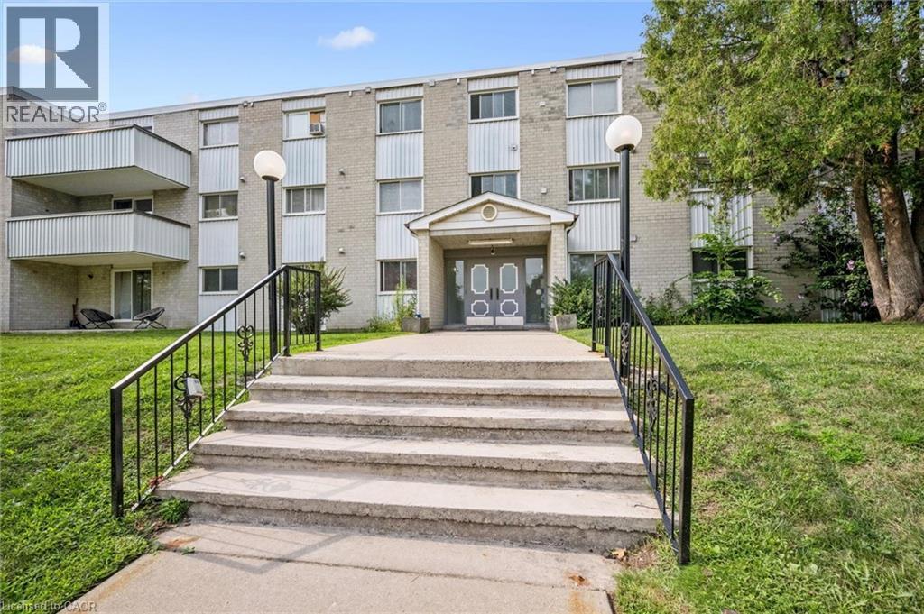 Concrete exterior with multiple balconies, a covered entrance, and mature landscaping - 6 Walton Avenue Unit# 107, Kitchener, ON - Outdoor