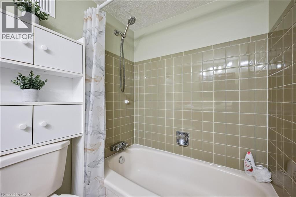 White cabinetry, ceramic wall tiling, and a bathtub with a shower fixture - 6 Walton Avenue Unit# 107, Kitchener, ON - Indoor Photo Showing Bathroom