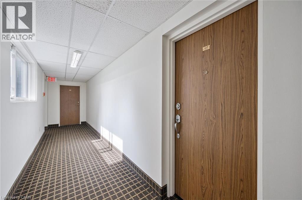 Wood-finish entry door with multiple locks and a peep-hole - 6 Walton Avenue Unit# 107, Kitchener, ON - Indoor Photo Showing Other Room