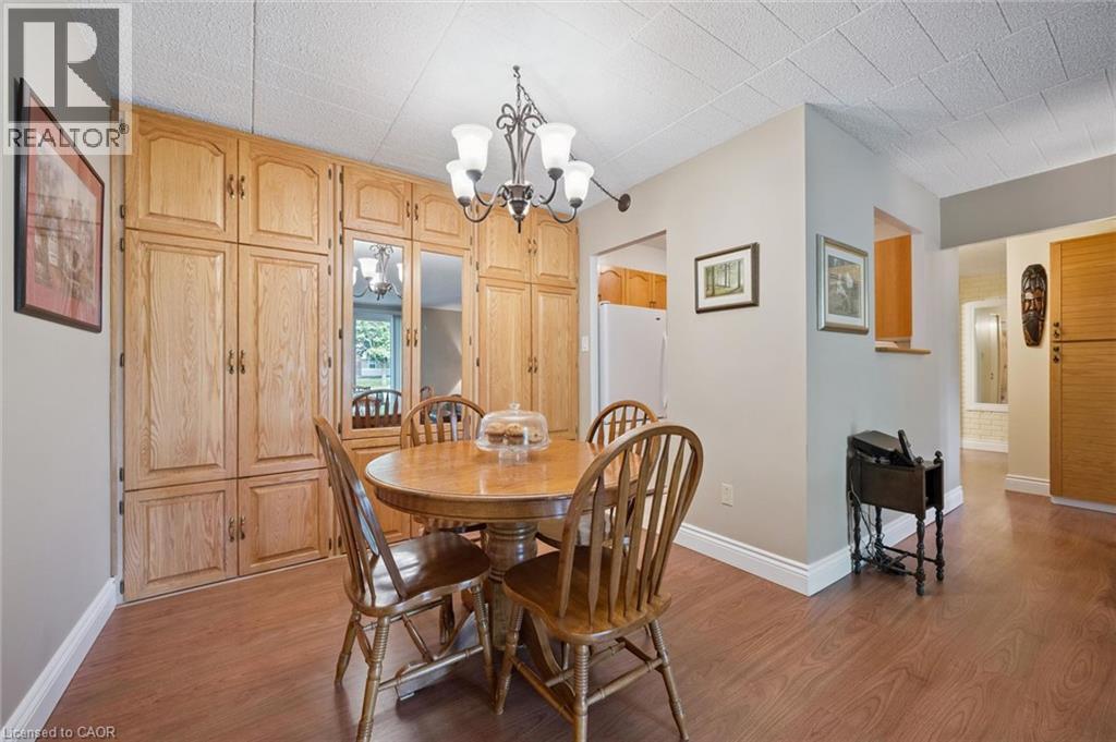 Extensive wood-finish cabinetry, wood-finish flooring, and a chandelier with decorative arms - 6 Walton Avenue Unit# 107, Kitchener, ON - Indoor Photo Showing Dining Room