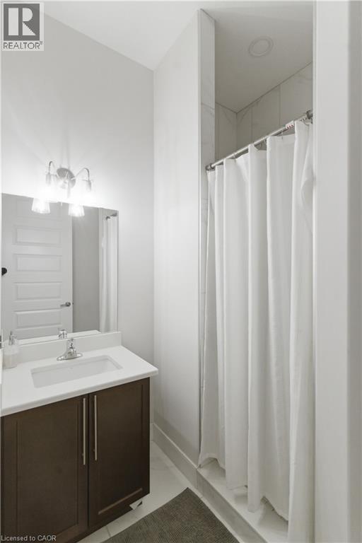 Modern bathroom featuring a dark wood vanity with brushed metal hardware, white quartz countertop, and an integrated sink - 2000 Maddex Way, London, ON - Indoor Photo Showing Bathroom