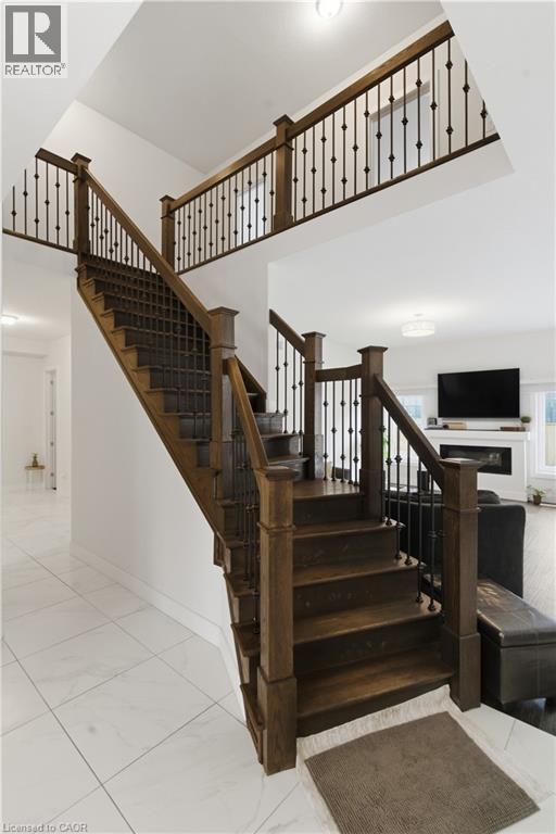 Elegant staircase featuring rich wood treads and newel posts with black metal spindle railings, ascending to a bright upper level - 2000 Maddex Way, London, ON - Indoor Photo Showing Other Room