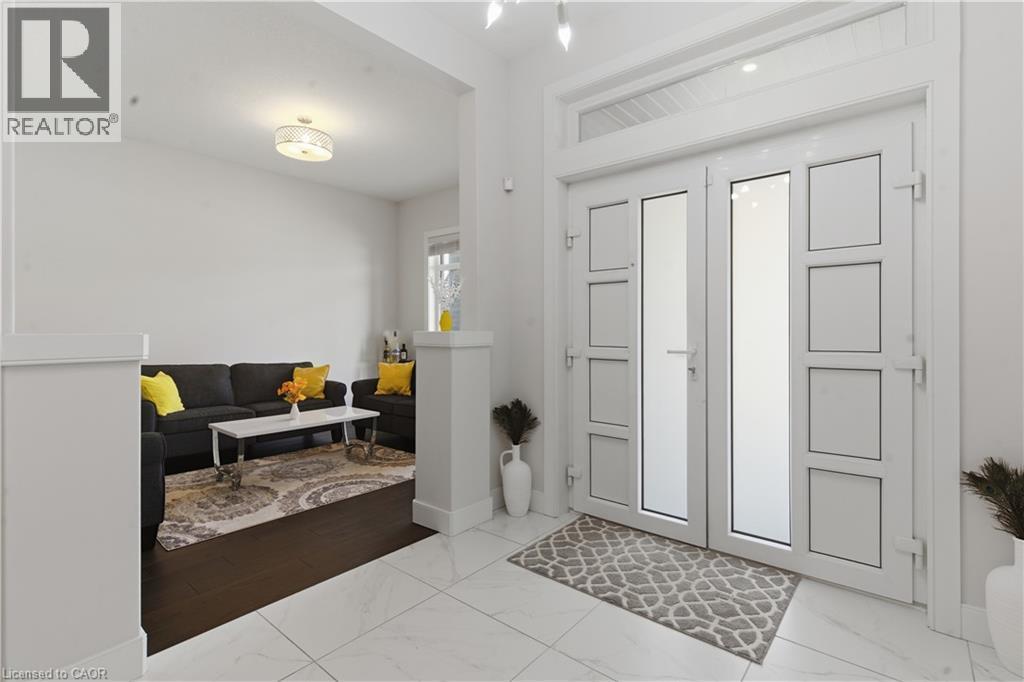 Bright, light-filled entry foyer featuring tile flooring, recessed ceiling lighting, and white paneled double doors with multiple glass panes - 2000 Maddex Way, London, ON - Indoor Photo Showing Other Room
