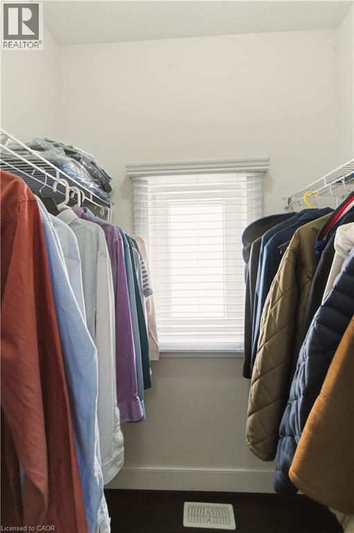 Walk-in closet with wire shelving, a window featuring blinds, and dark wood-finish flooring - 2000 Maddex Way, London, ON - Indoor With Storage