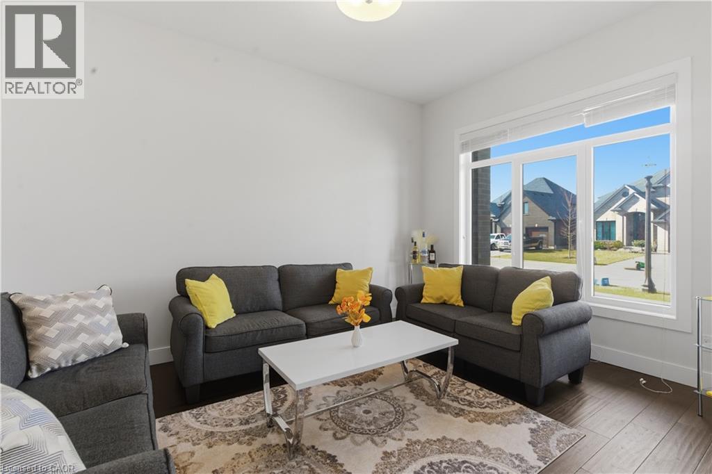Bright, light-filled living room anchored by large glass doors and windows framing outdoor scenery - 2000 Maddex Way, London, ON - Indoor Photo Showing Living Room