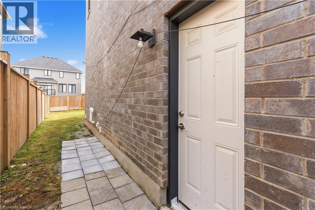 Brick exterior with a paneled exterior door, exterior light fixture, and a stone paver pathway - 2000 Maddex Way, London, ON - Indoor Photo Showing Other Room