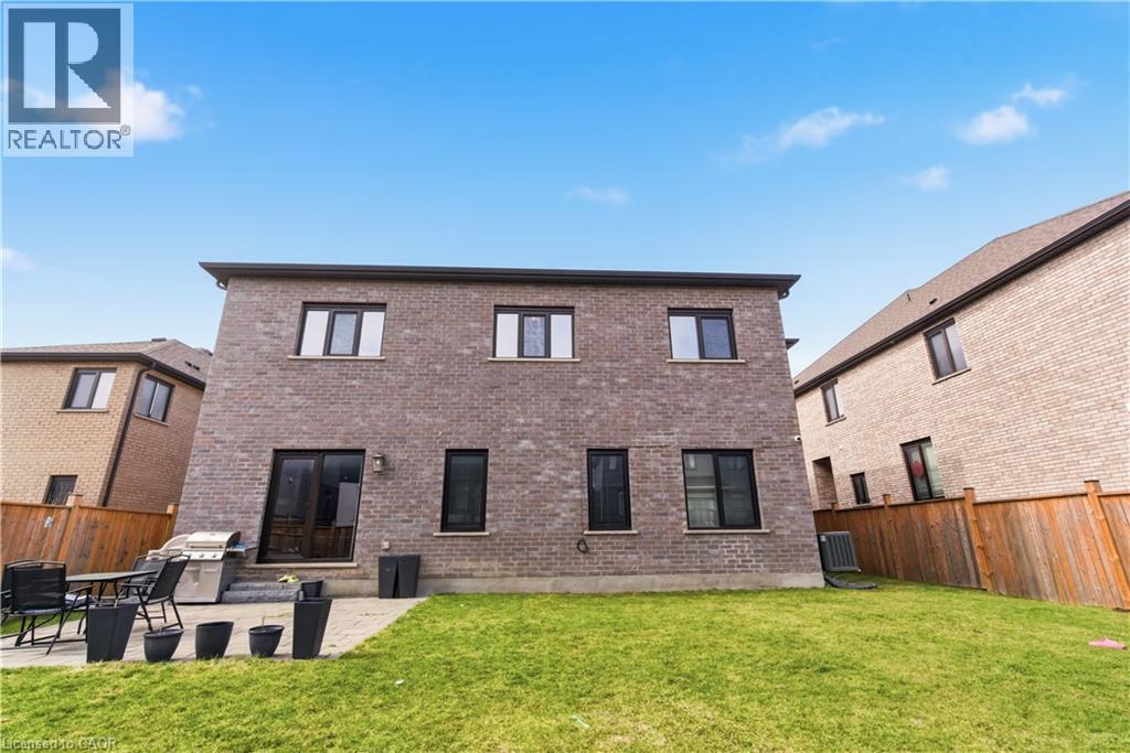 Brick exterior with multiple windows, concrete patio, and a grass lawn - 2000 Maddex Way, London, ON - Outdoor With Exterior