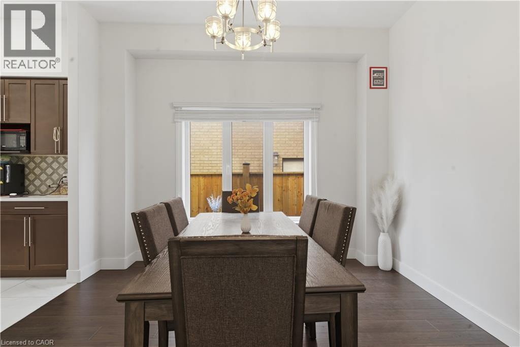 Formal dining space showcasing dark wood-finish flooring, a substantial dining table with upholstered chairs featuring nailhead trim, and a crystal chandelier - 2000 Maddex Way, London, ON - Indoor Photo Showing Dining Room
