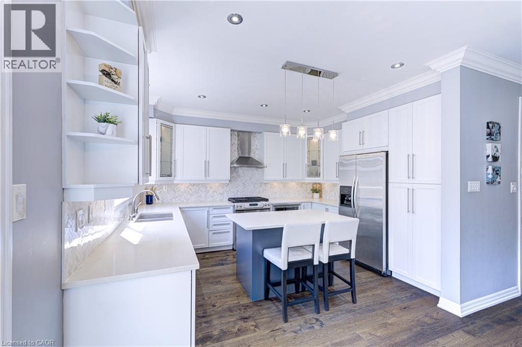 Contemporary kitchen with white cabinetry, stainless steel appliances, a center island with seating, pendant lighting, and wood-finish flooring - 1406 Marshall Crescent, Milton, ON - Indoor Photo Showing Kitchen With Double Sink With Upgraded Kitchen
