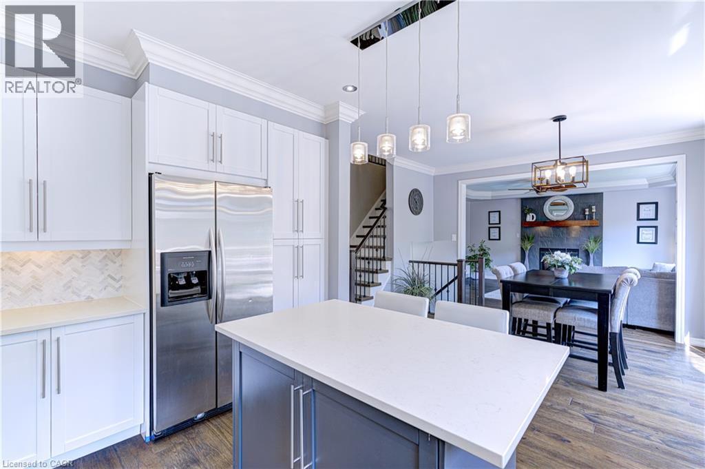 Contemporary kitchen featuring white shaker cabinetry, stainless steel appliances, a white herringbone tile backsplash, and a central island with a light-toned countertop - 1406 Marshall Crescent, Milton, ON - Indoor Photo Showing Kitchen