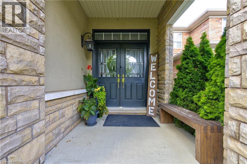 Stone facade entryway with double panel doors, transom window, and an exterior wall light - 1406 Marshall Crescent, Milton, ON - Outdoor