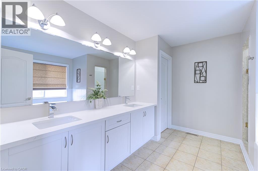 Double vanity with white cabinetry, integrated sinks, chrome faucets, and an expansive mirror - 1406 Marshall Crescent, Milton, ON - Indoor Photo Showing Bathroom