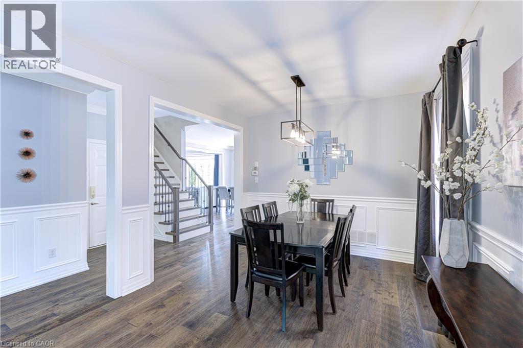 Formal dining area featuring wood-finish flooring, wainscoting, and a linear pendant light fixture - 1406 Marshall Crescent, Milton, ON - Indoor Photo Showing Dining Room