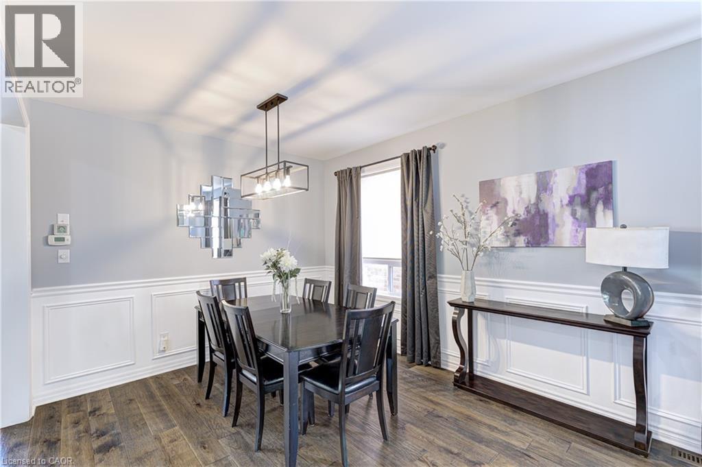 Formal dining area with wood-finish flooring, white wainscoting, and a modern chandelier - 1406 Marshall Crescent, Milton, ON - Indoor Photo Showing Dining Room