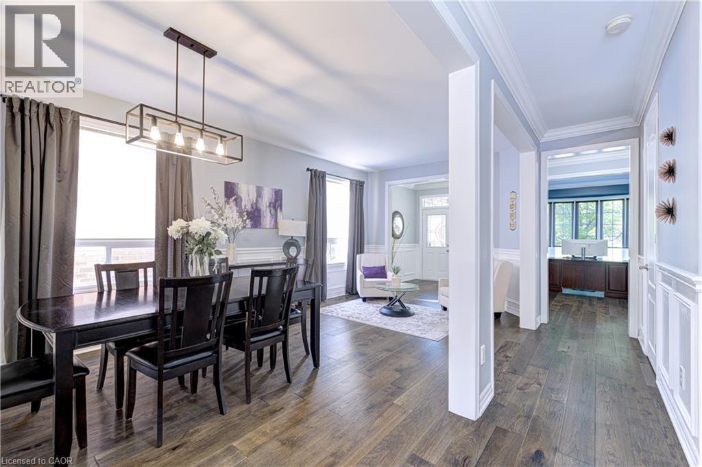Open-concept interior featuring wood-finish flooring, a linear pendant light fixture, extensive crown molding, and wainscoting details - 1406 Marshall Crescent, Milton, ON - Indoor Photo Showing Dining Room