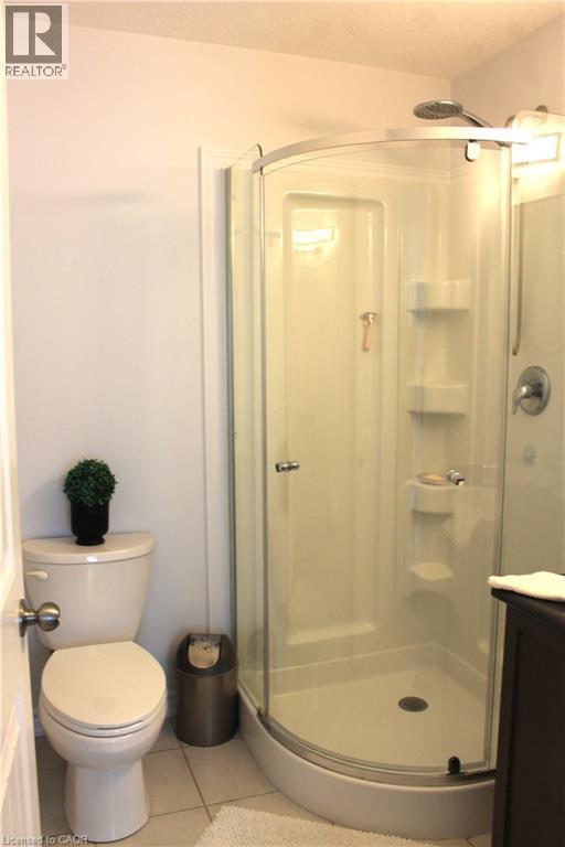 Curved glass shower enclosure with integrated shelving and a chrome showerhead - 12 Poplar Drive Unit# 21, Cambridge, ON - Indoor Photo Showing Bathroom