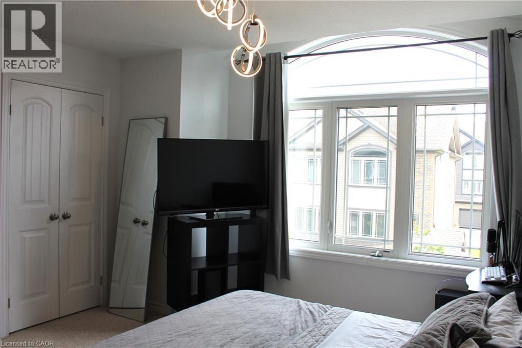Arched transom window above a multi-pane window unit, contemporary light fixture, and white bi-fold closet doors - 12 Poplar Drive Unit# 21, Cambridge, ON - Indoor Photo Showing Bedroom