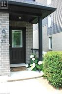 Covered entry with gray brick facade, black front door with glass panel, and exterior lighting fixture -