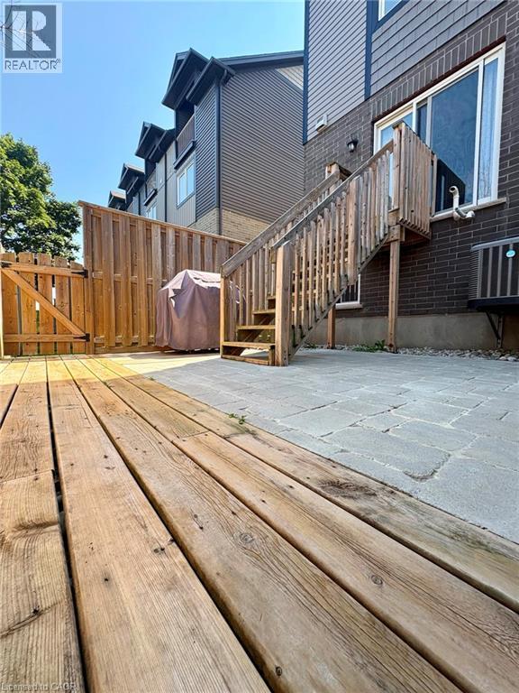 Wood deck with a privacy fence, stone paver patio, exterior brick, and a wood staircase - 12 Poplar Drive Unit# 21, Cambridge, ON - Outdoor With Exterior