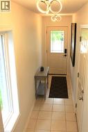 Entryway featuring contemporary ceiling light fixtures, a white paneled entry door with decorative glass, and square tile flooring -