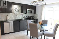 Dark wood-finish cabinetry with stainless steel hardware, mosaic tile backsplash, stainless steel appliances, and tile flooring -