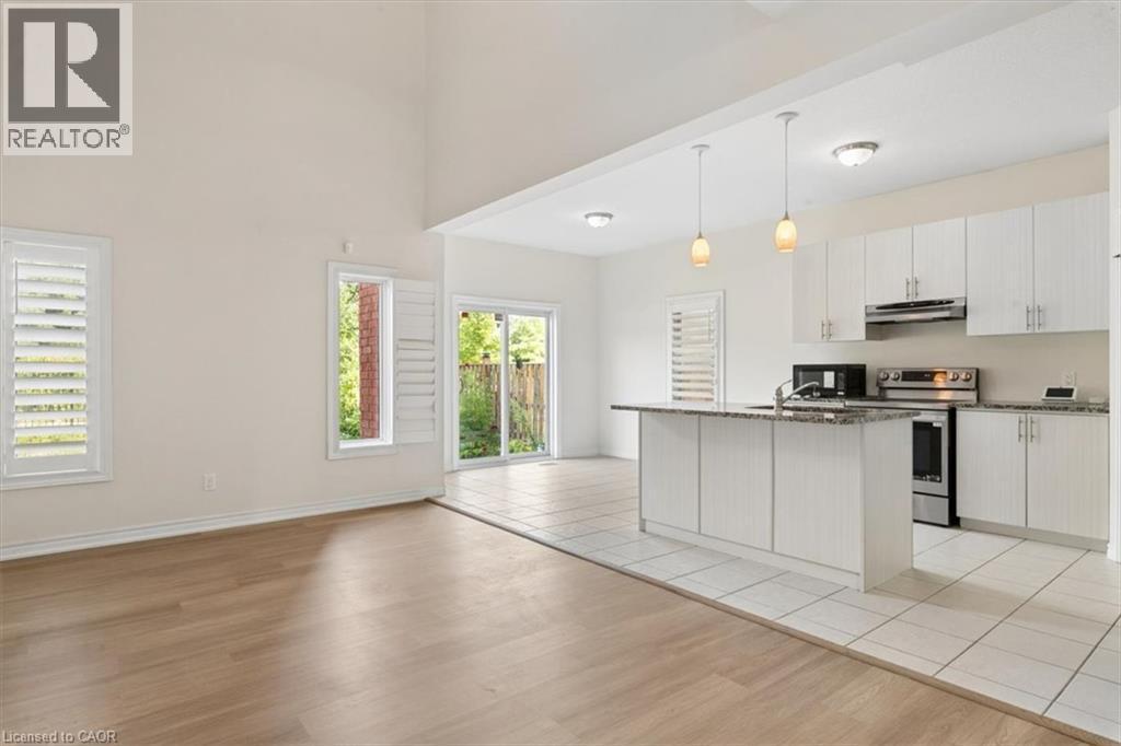 Vaulted ceiling, wood-finish flooring, white plantation shutters, white kitchen cabinetry, and stainless steel appliances - 242 Moorlands Crescent, Kitchener, ON - Indoor Photo Showing Kitchen