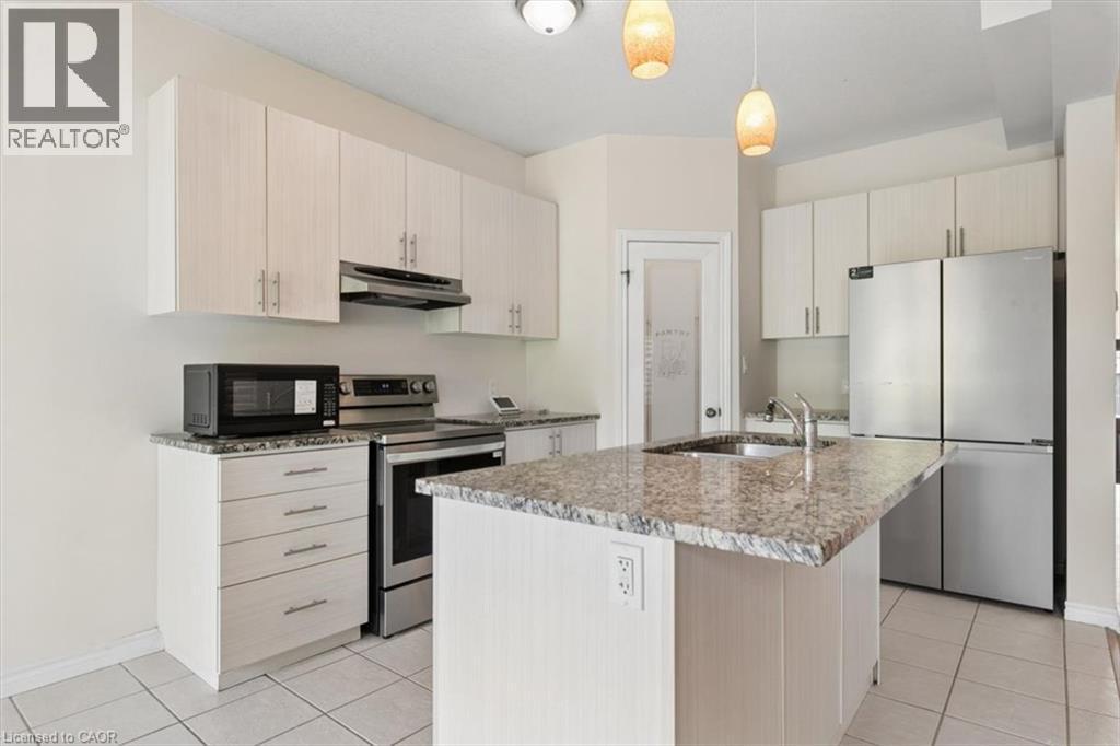 Kitchen featuring an island with an undermount sink, granite countertops, light wood-finish cabinetry, stainless steel appliances, and tile flooring - 242 Moorlands Crescent, Kitchener, ON - Indoor Photo Showing Kitchen With Upgraded Kitchen
