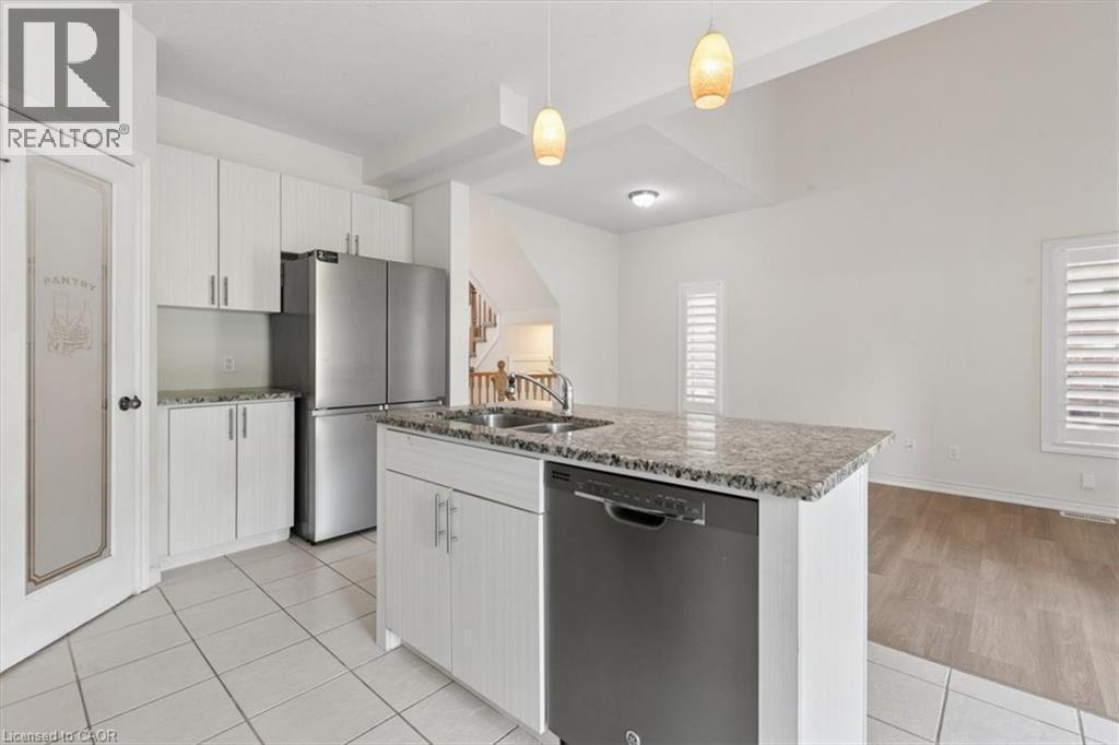 Kitchen with white cabinetry, stainless steel appliances, a center island with sink, and stone countertops - 242 Moorlands Crescent, Kitchener, ON - Indoor Photo Showing Kitchen With Double Sink