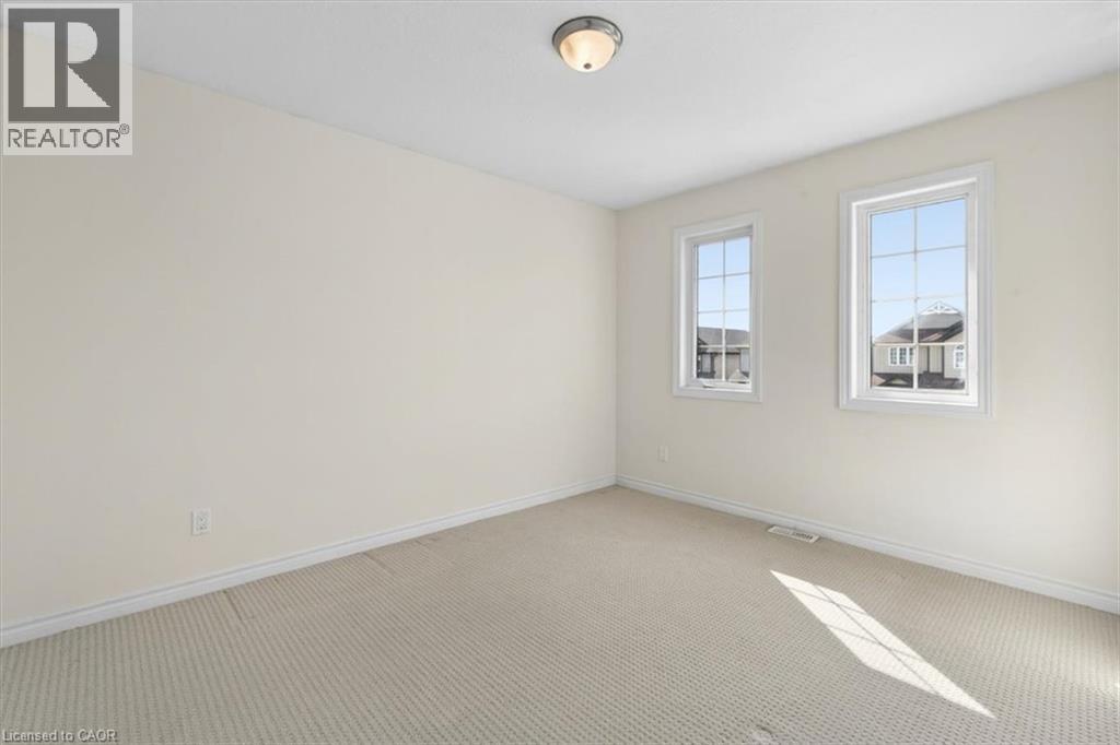 Neutral wall tones, wall-to-wall carpeting, two windows with white trim, and a ceiling-mounted light fixture - 242 Moorlands Crescent, Kitchener, ON - Indoor Photo Showing Other Room